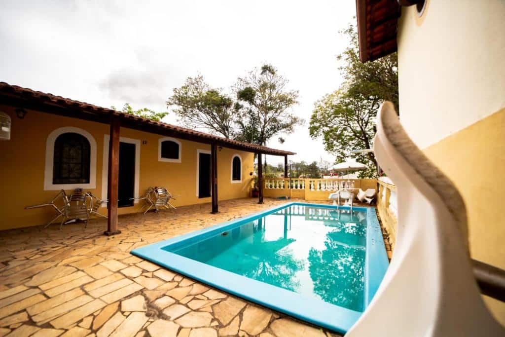Piscina da Pousada do Ipê, com vista para a natureza, com cadeiras e mesas ao redor do local