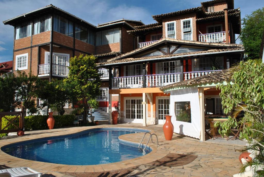 Vista da Pousada Ananda-ri com a piscina logo na frente, local amplo, uma construção com muitas sacadas e em tijolinhos