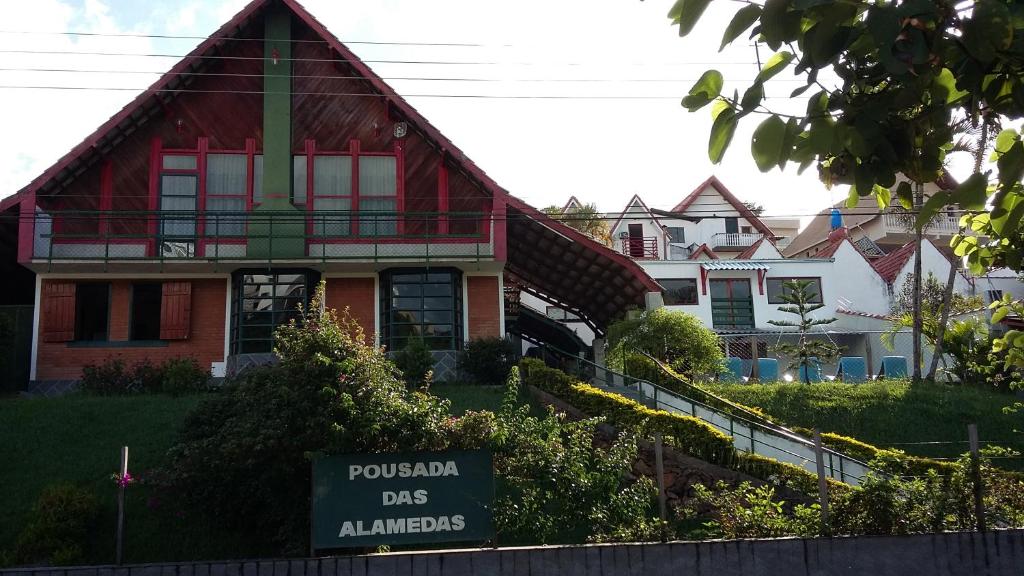 Entrada da Pousada das Alamedas, local com enorme jardim, uma construção com dois andares, em tijolinhos e pintada de vermelho