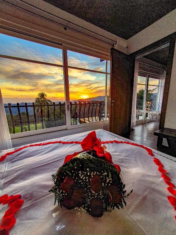 Quarto da Pousada La Vista. Uma cama de casal decorada e com buquê. De frente para a parede de vidro do quarto com vista para o jardim. Foto para ilustrar post sobre pousadas pet friendly em Gramado.