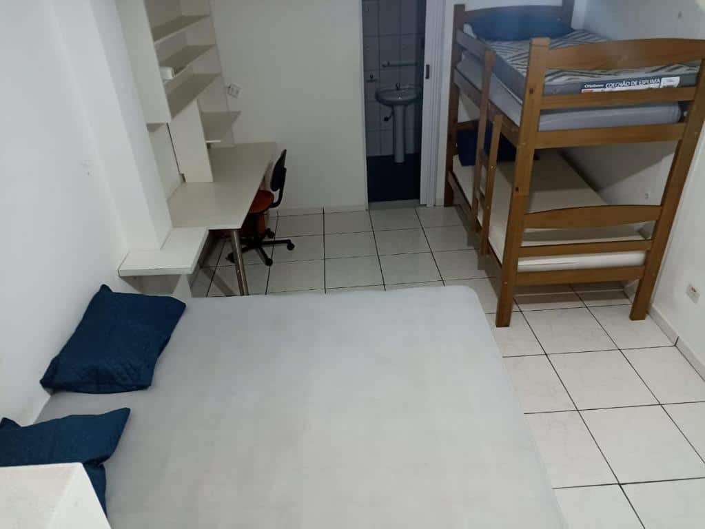 Foto do quarto no Residencial Marina Del Sol. Representa o post sobre airbnb em Paúba. Uma cama está na esquerda e de frente pra ela há uma beliche. Do lado da cama de casal há uma escrivaninha com cadeira. Do lado da beliche há uma porta estreita para o banheiro. 