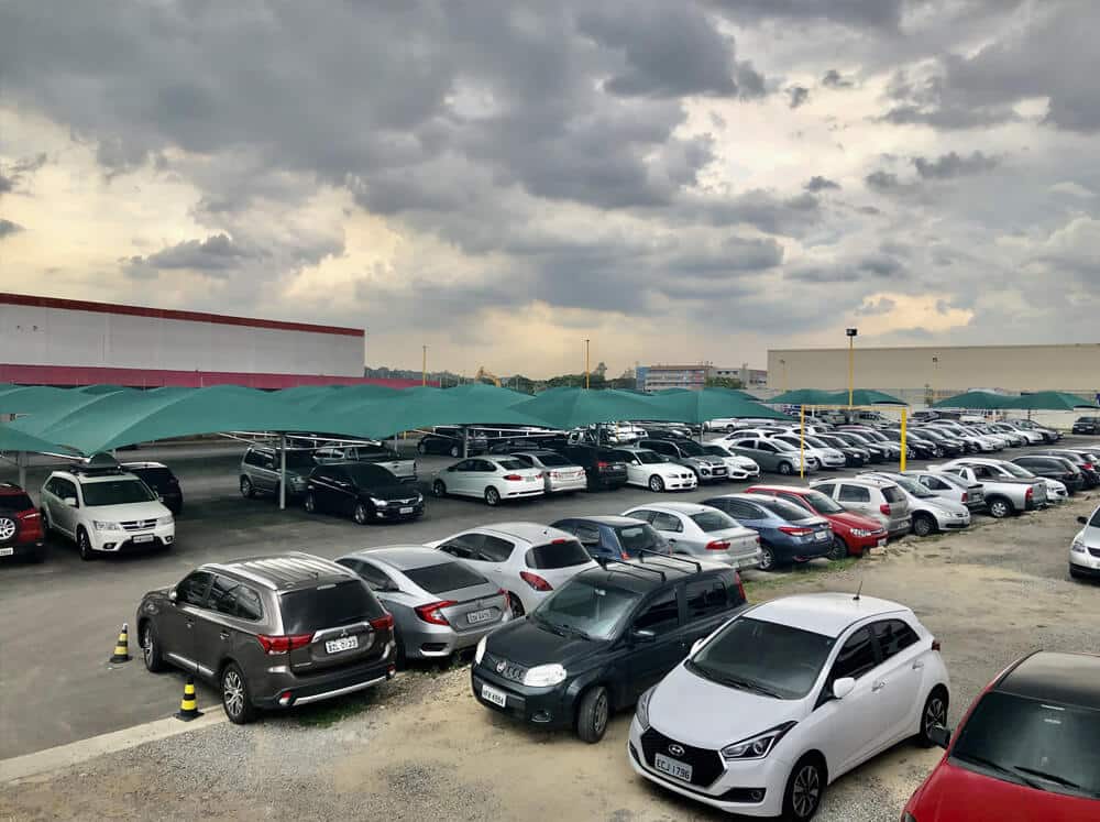 Espaço externo do Aero Park com fileiras de carros ao ar livre e outras fileiras cobertas por toldos verdes