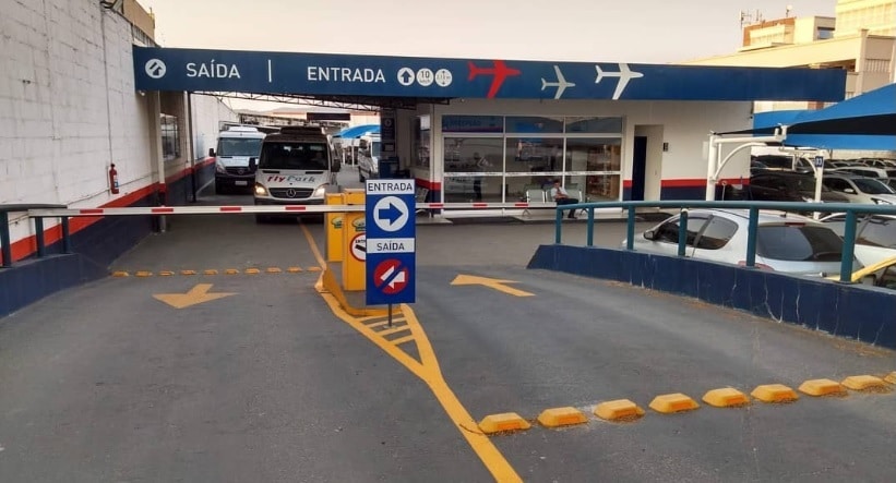 Entrada e saída do Fly Park com cerca automatizada, vagas descobertas e algumas vans circulando