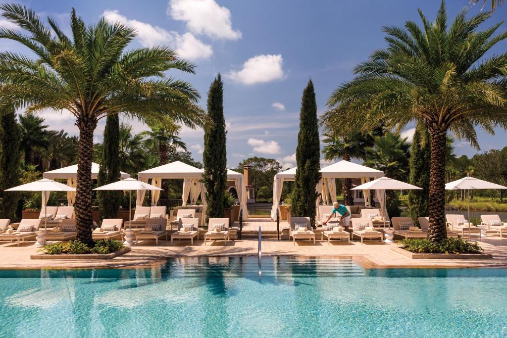 piscina do Four Seasons Resort Orlando, um dos hotéis de luxo em Orlando com árvores espelhadas e cadeiras e mesinhas cobertas
