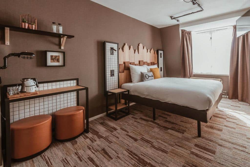 Quarto do Mr. Jordaan, com cama de casal e balcão com dois puffs e amenidades para café em cima. Há uma janela no lado direito iluminando o quarto