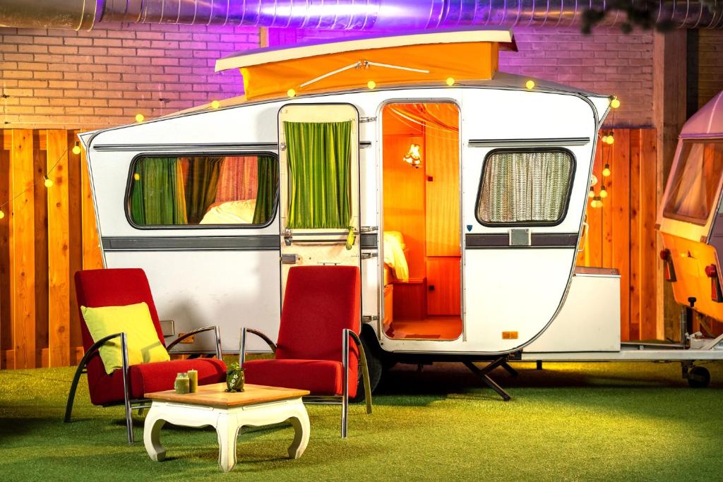 Caravana vintage do Outside Inn, um dos melhores hotéis em Amsterdam, com cadeiras na frente, gramado artificial e bastante iluminação