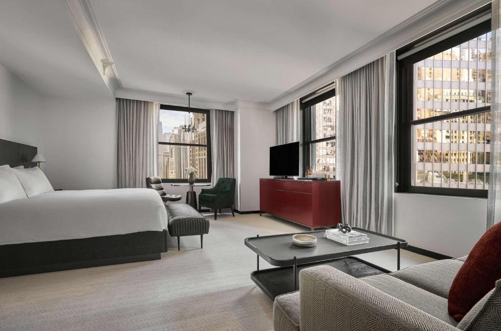 Quarto espaçoso do Pendry Chicago com uma cama king size, área de estar, janelas grandes, TV, cômoda e vista para a cidade do lado de fora, para representar hotéis em Chicago.