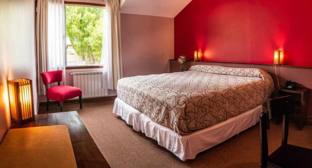 Quarto do Pudu Lodge com cama de casal do lado direito da imagem com uma cômoda em cada lado da cama, para representar hotéis em El Chalten.