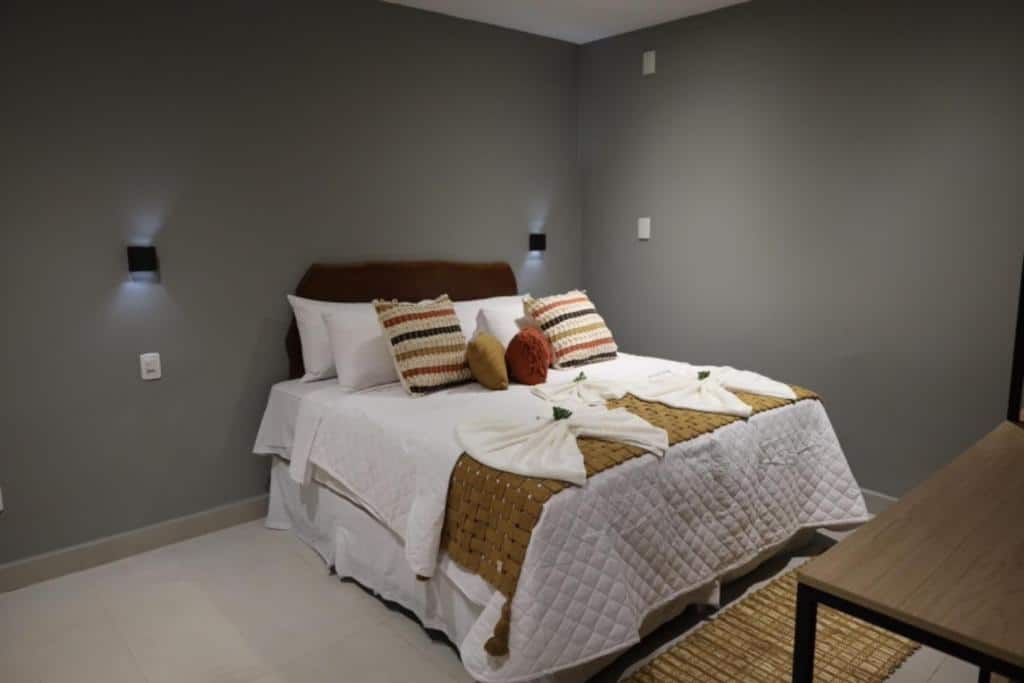 Quarto da Villa Xodó. Uma cama de casal no meio com várias almofadas e toalhas. De cada lado um lustre. Foto para ilustrar post sobre hotéis em Fernando de Noronha.