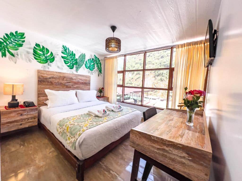suíte do rupa rupa high jungle eco B&B com uma mesa de madeira com cadeira no canto direito e uma cama de casal no lado esquerdo da imagem, ao fundo há uma grande janela com vista para as montanhas