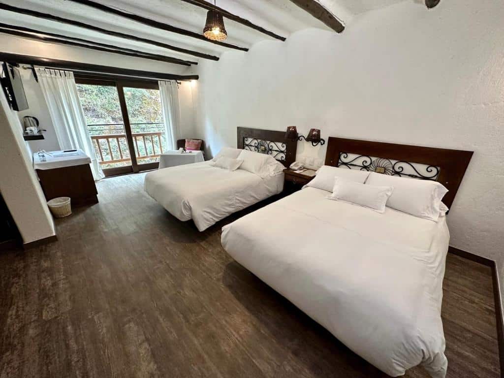 suíte do hatun inti boutique com duas camas de casal à direita do quarto e uma varanda privativa com vista para a vegetação