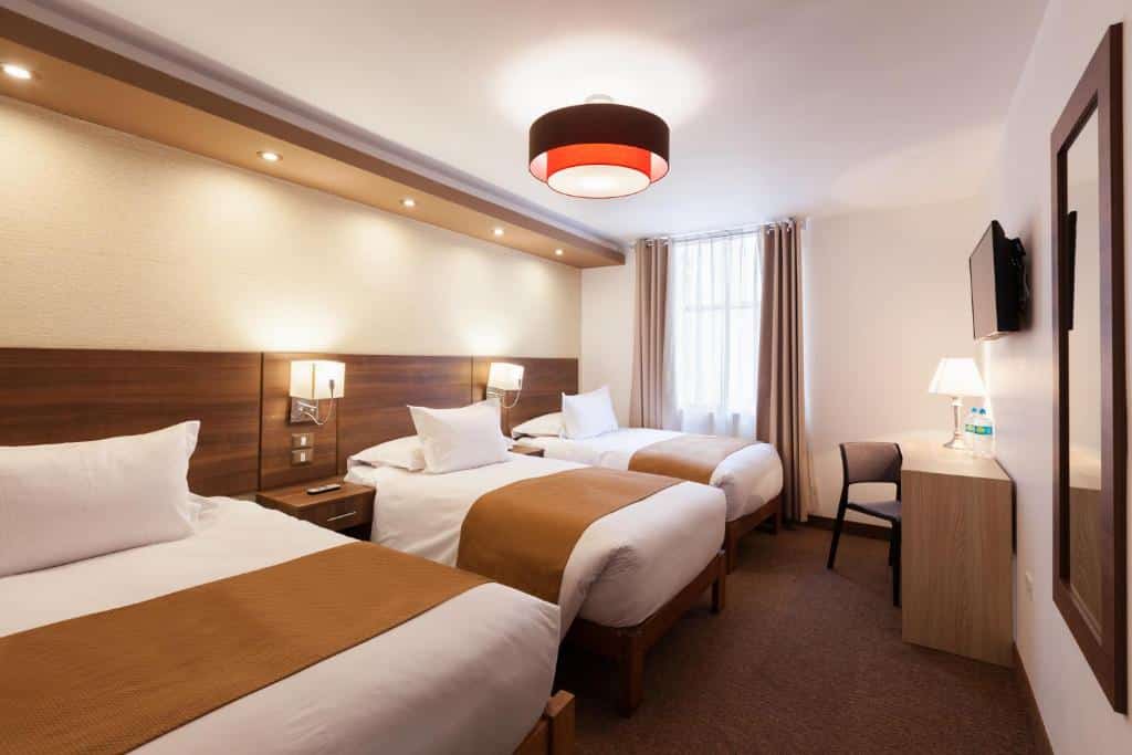 quarto triplo do inti punku machupicchu hotel com três camas dispostas no lado esquerdo do quarto e um espelho na vertical, preso à parede em frente às camas