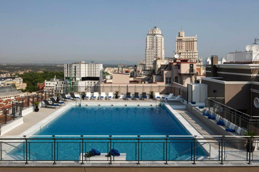 Piscina do hotel Emperador cercada por espreguiçadeiras com grades ao redor. O local tem vista para a cidade.
