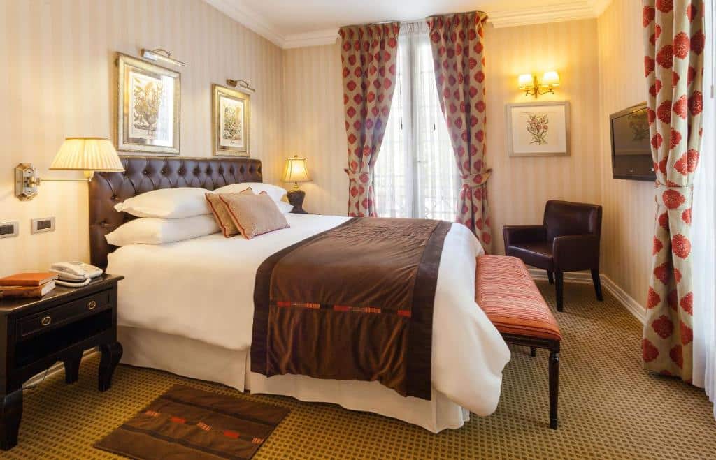 Quarto do Hotel Boutique Le Reve com cama de casal no centro, duas cômodas de madeira e em frente a cama uma mesa de trabalho com cadeira e em cima na parede uma TV. Representa hotéis em Providencia em Santiago.