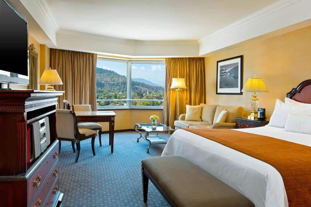 Quarto do Sheraton Santiago Hotel & Convention Center com cama de casal do lado direito com duas cômodas do lado da cama com luminárias em cima, do lado direito ainda tem uma poltrona estofada. Representa hotéis em Providencia em Santiago.