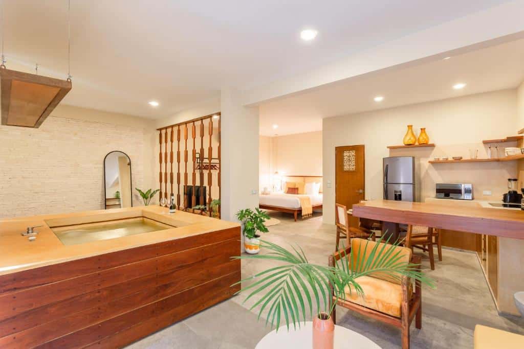 Estúdio do Xperience Tulum Hotel, de 68 m², com banheira de hidromassagem, cozinha com geladeira e micro-ondas, mesa, sala de estar, e quarto com cama de casal e TV, para representar hotéis em Tulum.