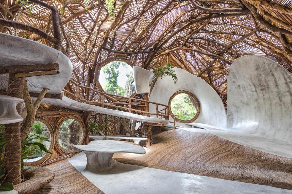 Espaço rústico do Azulik, um dos hotéis em Tulum, com paredes e teto com decoração feita de galhos de árvore e madeira e bastante natureza em volta