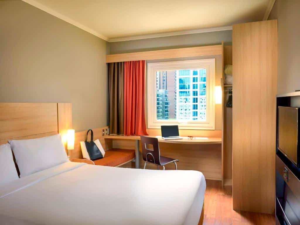 Quarto do ibis Santiago Las Condes Manquehue com cama de casal do lado esquerdo e do lado esquerdo do quarto mesa de trabalho com janela, para representar hotéis Mercure em Santiago.