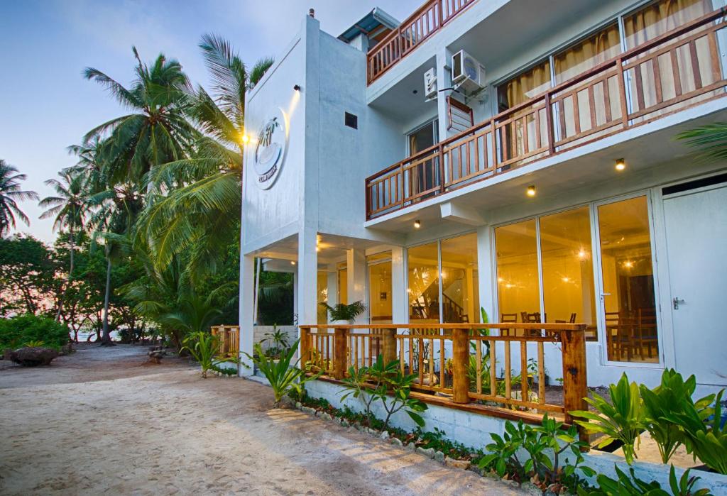 Prédio do Island Break, com as luzes ligadas dentro, num início de noite. O local fica à beira-mar, com areia em volta e várias árvores