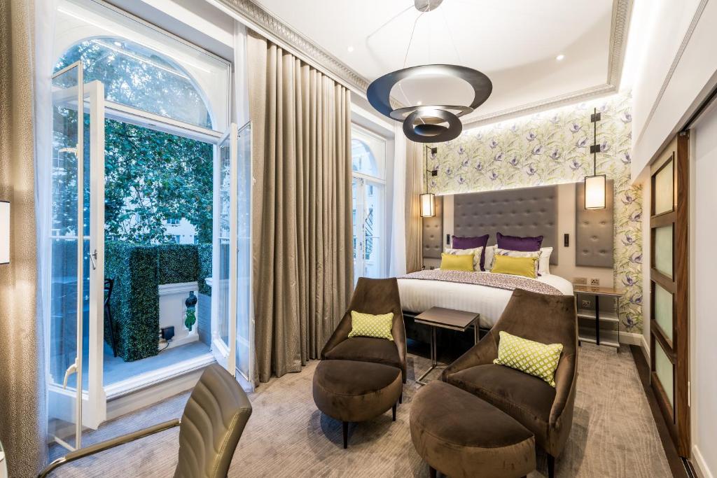 Quarto no Mercure London Hyde Park Hotel com uma cama de casal, duas poltronas, uma varanda que leva para um pequeno jardim, chão de carpete, tudo decorado em tons de marrom, para representar hotéis em Londres para brasileiros
