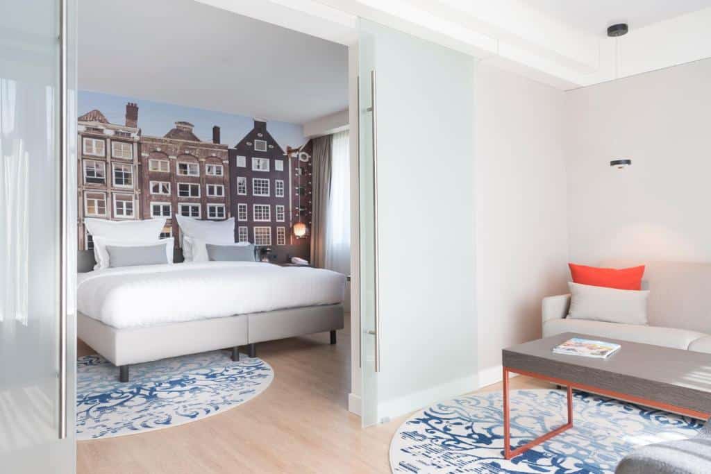 Quarto do Steigenberger Airport Hotel Amsterdam, de 34 m², com cama de casal e uma sala de estar com mesa de centro e um sofá.