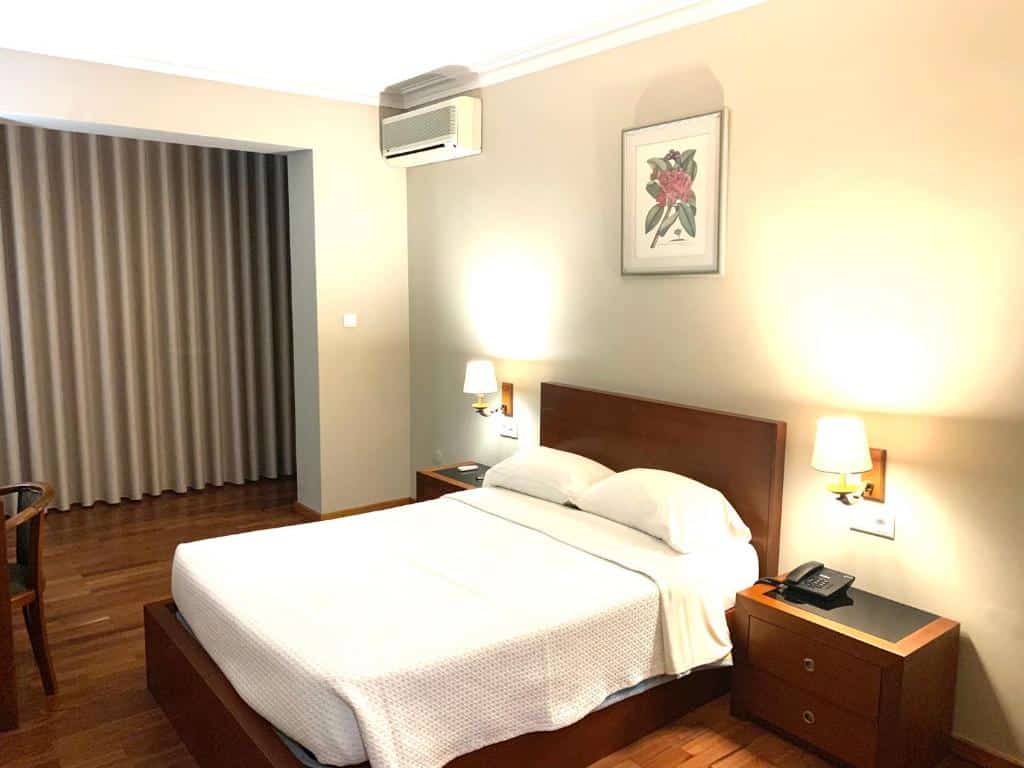 Quarto do Hotel Puma com cama de casal do lado direito com duas cômodas em cada lado da cama. Representa hotéis perto do aeroporto do Porto.
