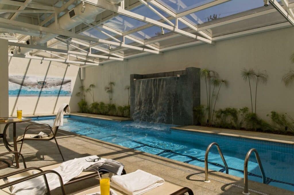 Piscina comprida com uma pequena que d'água no Intercity São Paulo Nações Unidas com um teto de vidro sob a piscina, o deck também é pequeno e conta com espreguiçadeiras