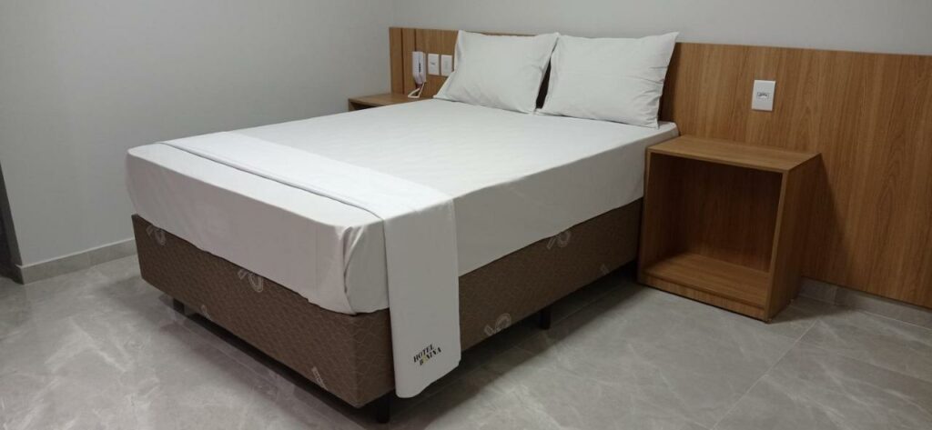 Quarto do Hotel Bonina. Uma cama de casal, de cada lado uma cômoda. Imagem para ilustrar post sobre hotéis perto do Expo Center Norte.