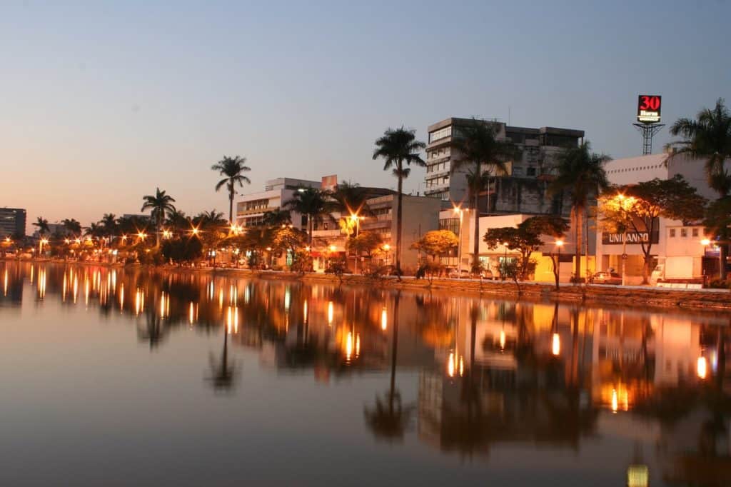 Lagoa com reflexo de árvores e prédios em Sete Lagoas, Minas Gerais