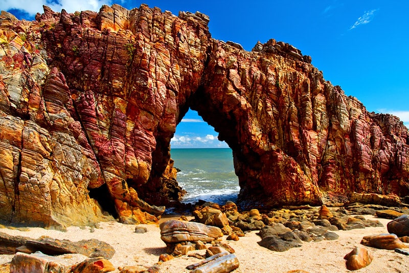 Imagem da Pedra Furada em Jericoacoara, uma formação rochosa com um buraco no meio, por qual podemos ver o mar.