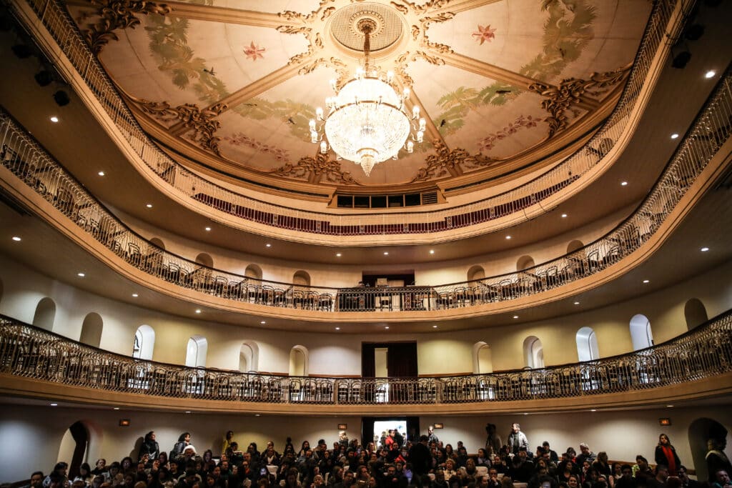 Teatro cheio do Theatro São Pedro, com um lustre no centro.