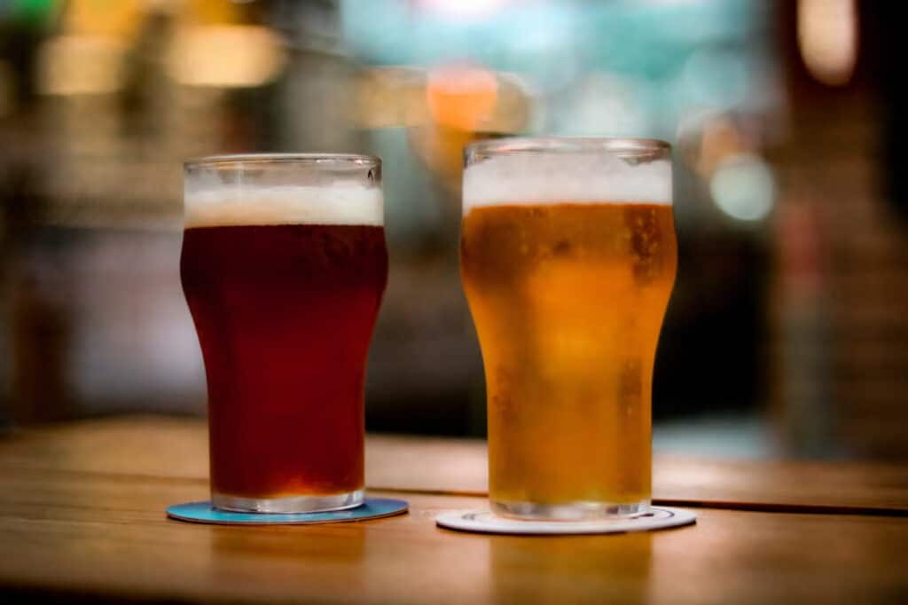 Uma mesa com duas cervejas de cores diferentes.