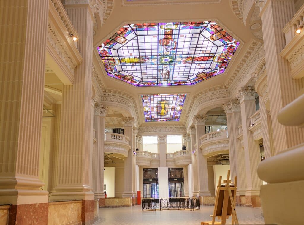 Parte interna do Farol Santander. Um teto com artes de viro eum prédio laro e vazio.
