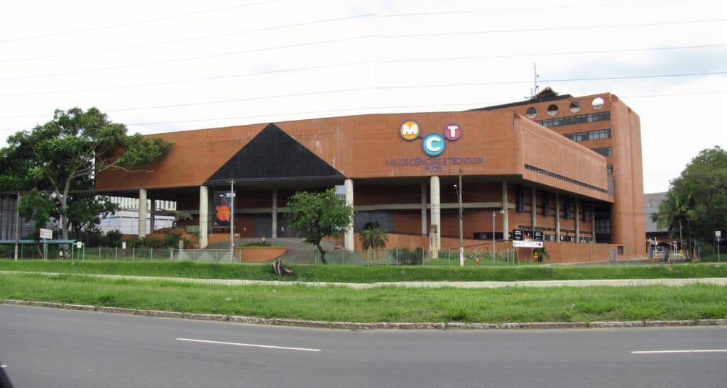 Fachada da frente do Museu de Ciência e Tecnologia em Porto Alegre. Uma rua, e uma calçada na frente, atrás o prédio.