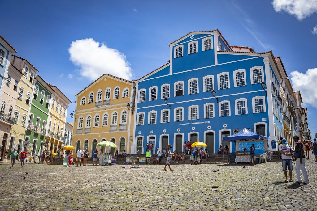 Uma rua vibrante em Pelourinho com prédios coloniais coloridos em tons de azul, amarelo e verde. .