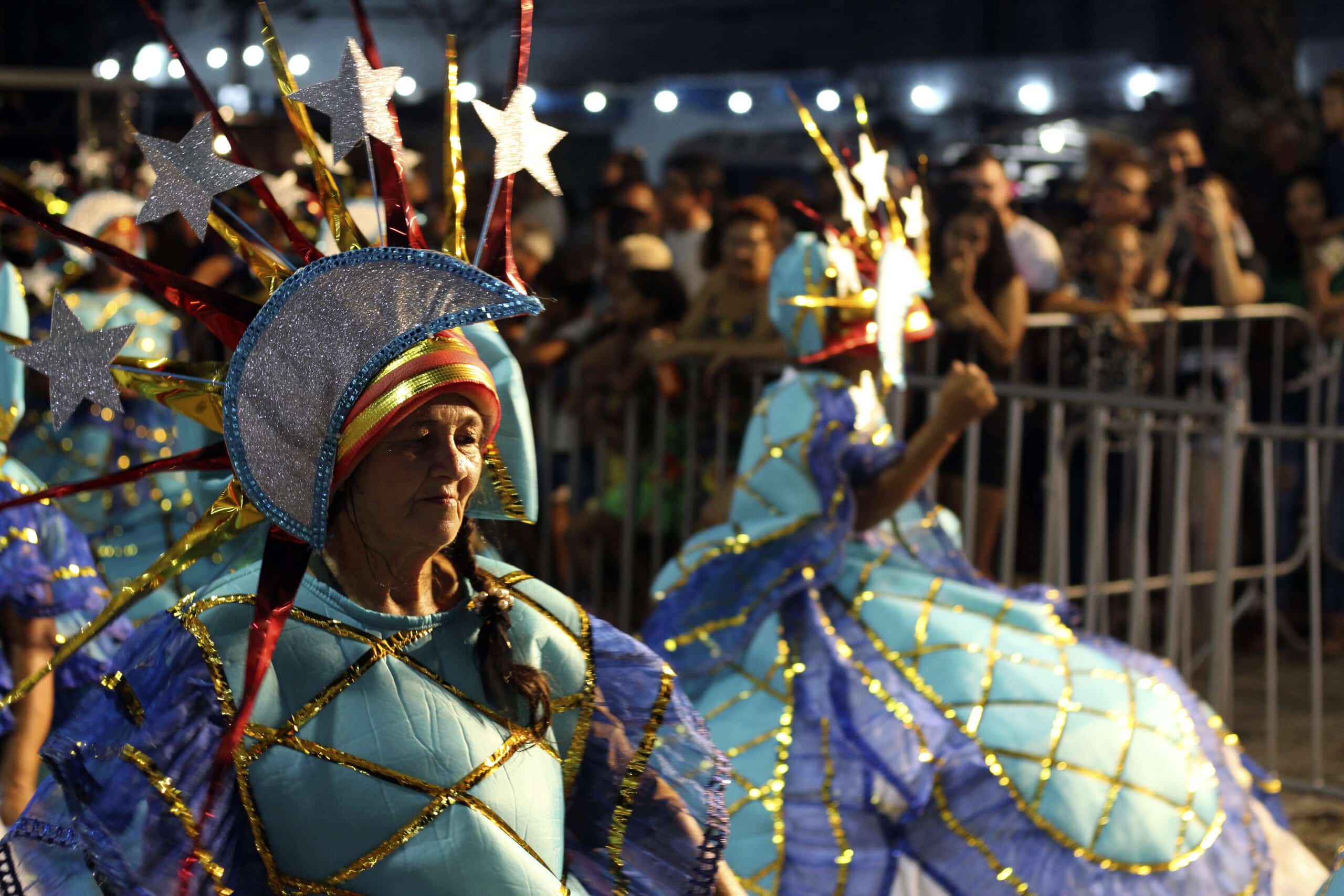 Uma mulher com um traje colorido e um capacete participa de um desfile de Carnaval em Natal.