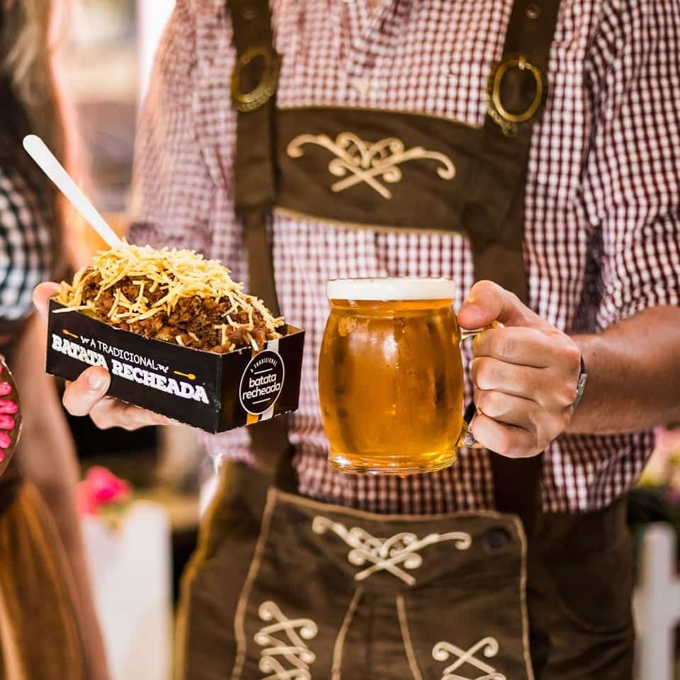 Pessoa segurando batata recheada e cerveja gelada na Oktoberfest