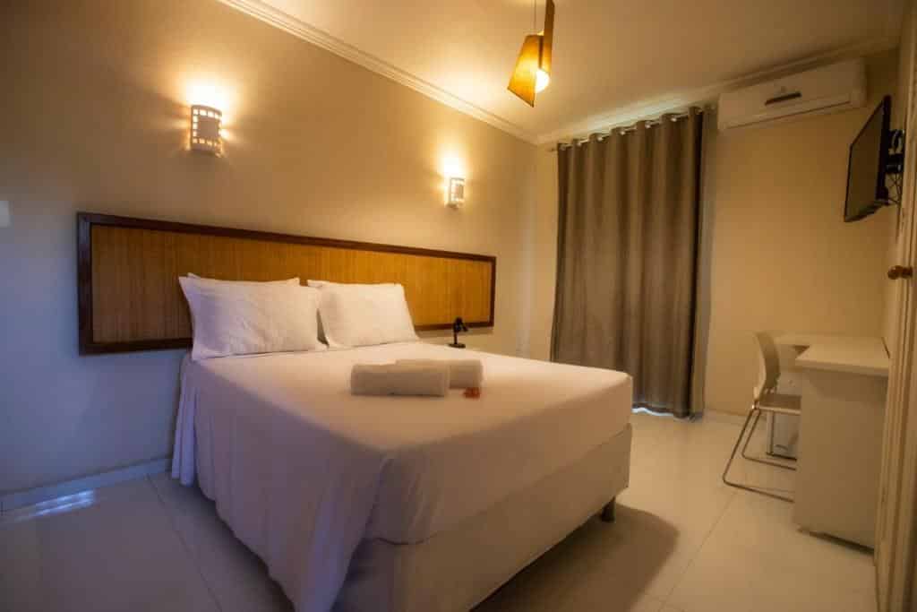 Quarto da Pousada Aruana Praia, com cama de casal, mesa de trabalho, ar-condicionado e TV
