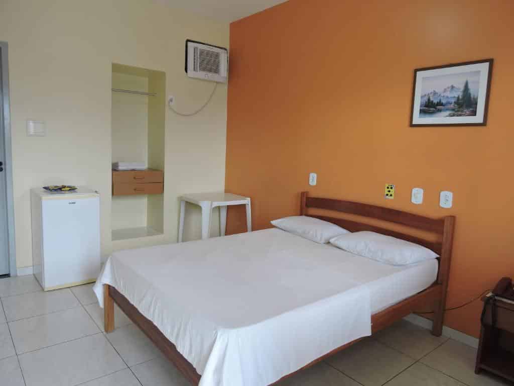 Quarto da Pousada Raio de Sol com cama de casal, frigobar, ar-condicionado e quadro na parede