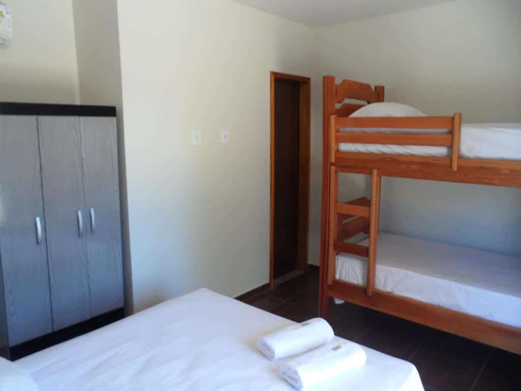 Um quarto simples da Pousada Eolos com uma cama de casal, um beliche de madeira, um guarda-roupa e duas toalhas enroladas na cama. Representa o post de pousadas em Barra Grande no Piauí.