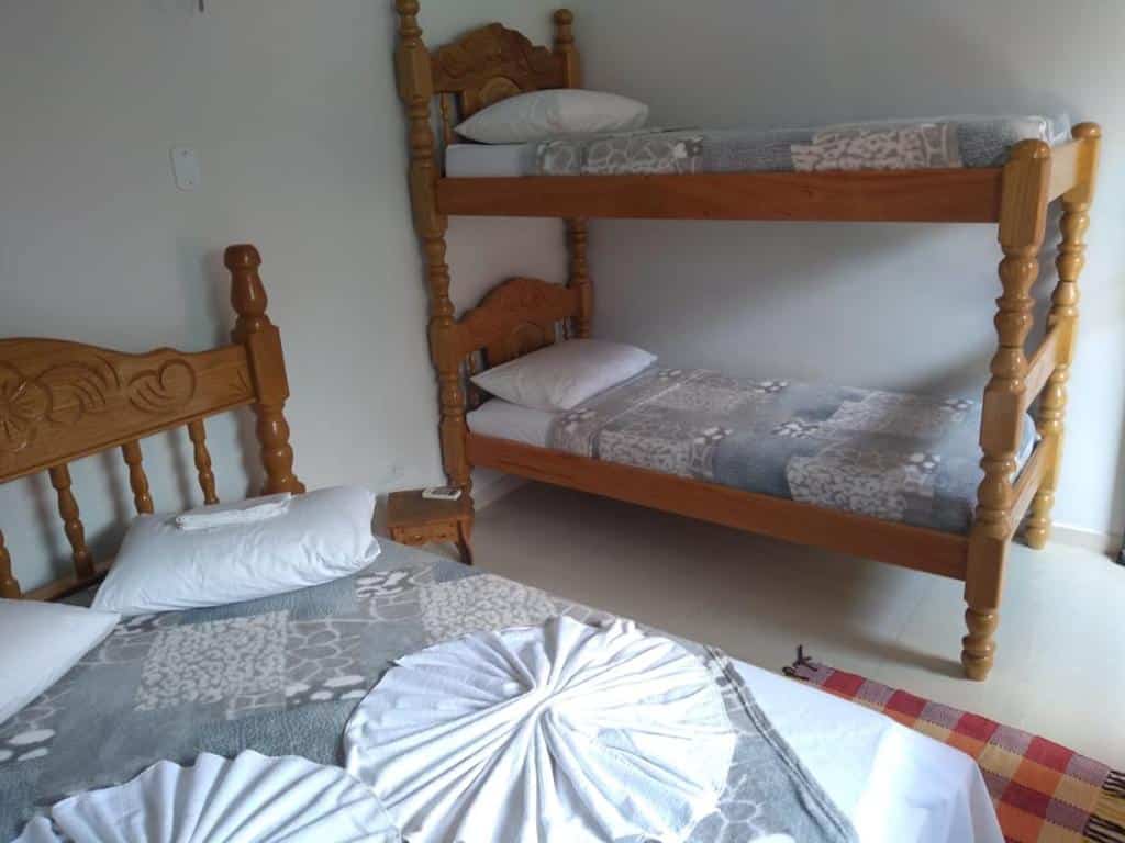 quarto da Pousada Mandala com um beliche de madeira e uma cama de casal, ambos com roupas de cama estampadas e travesseiros brancos. Esta é uma das pousadas em Bonito.