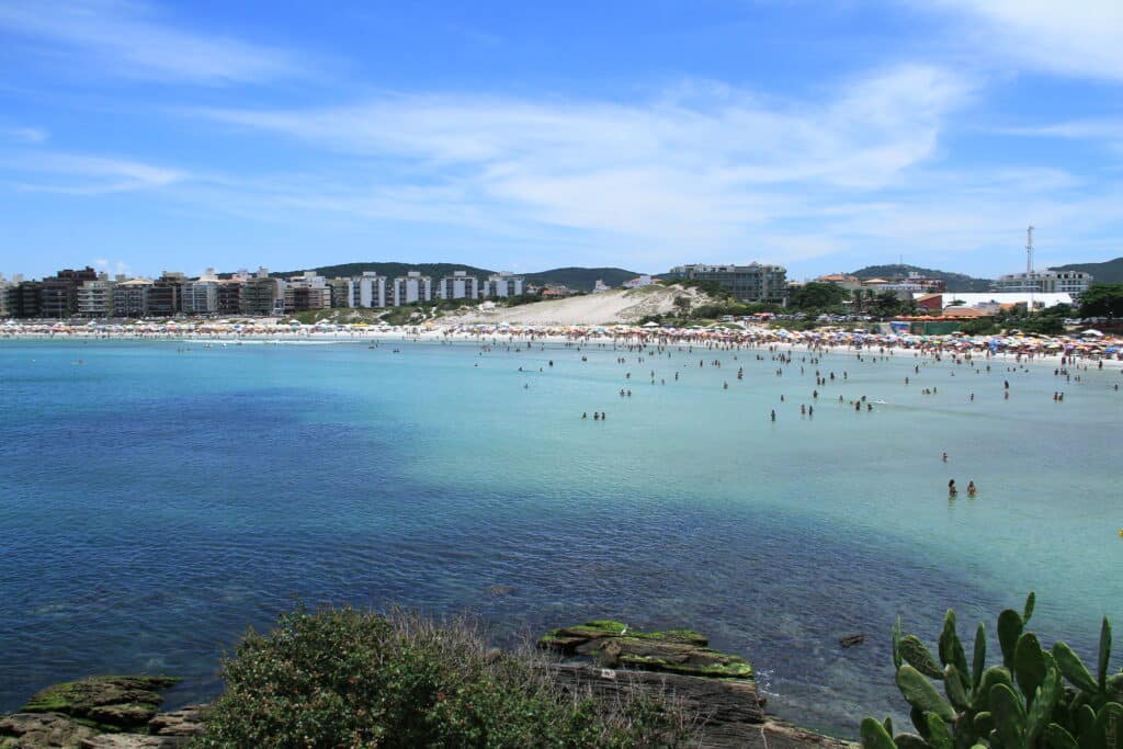 Vista de uma praia em Cabo Frio com mar de água em tonalidades distintas, metade escura e metade clara