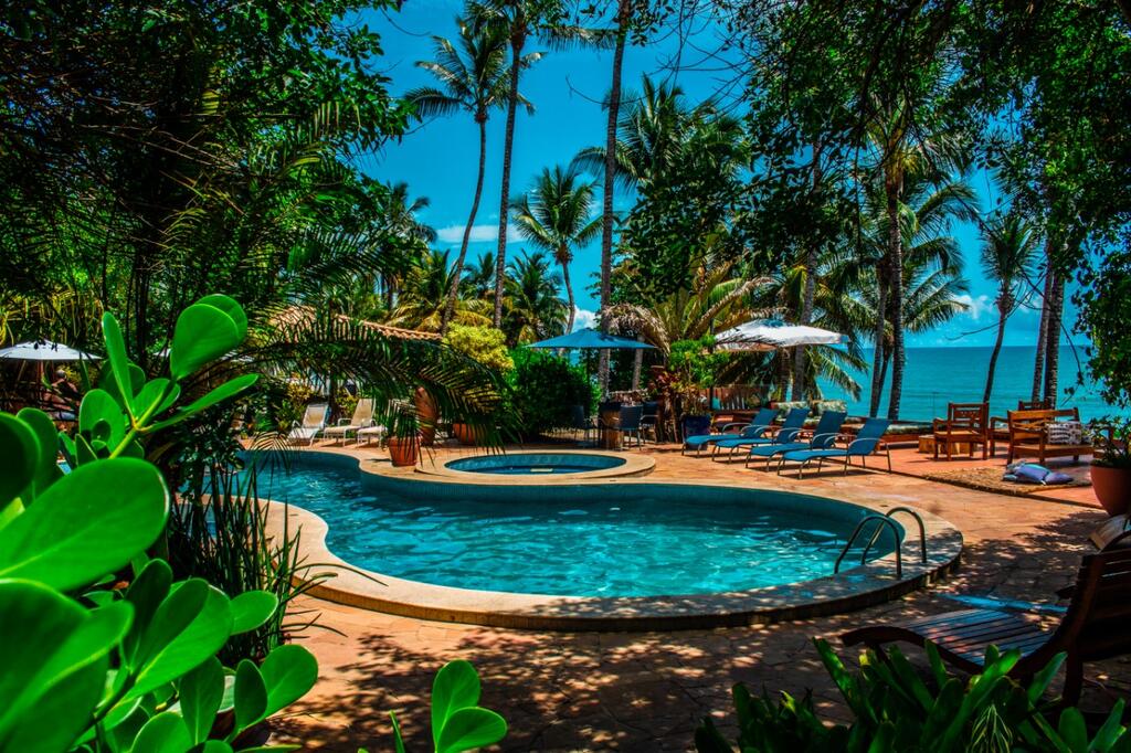 Piscina da pousada Morro dos Navegantes, em Ilhéus, com vista para o mar e exuberante vegetação ao redor